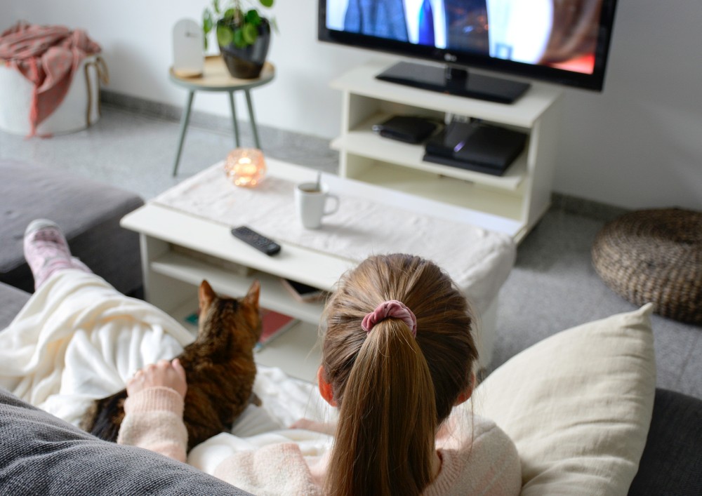 Mujer con su gato viendo la televisión durante la pandemia